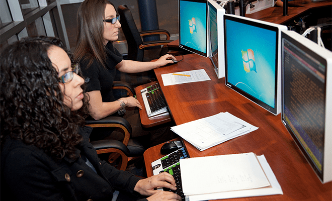 Two female students sitting side by side in a computer lab 